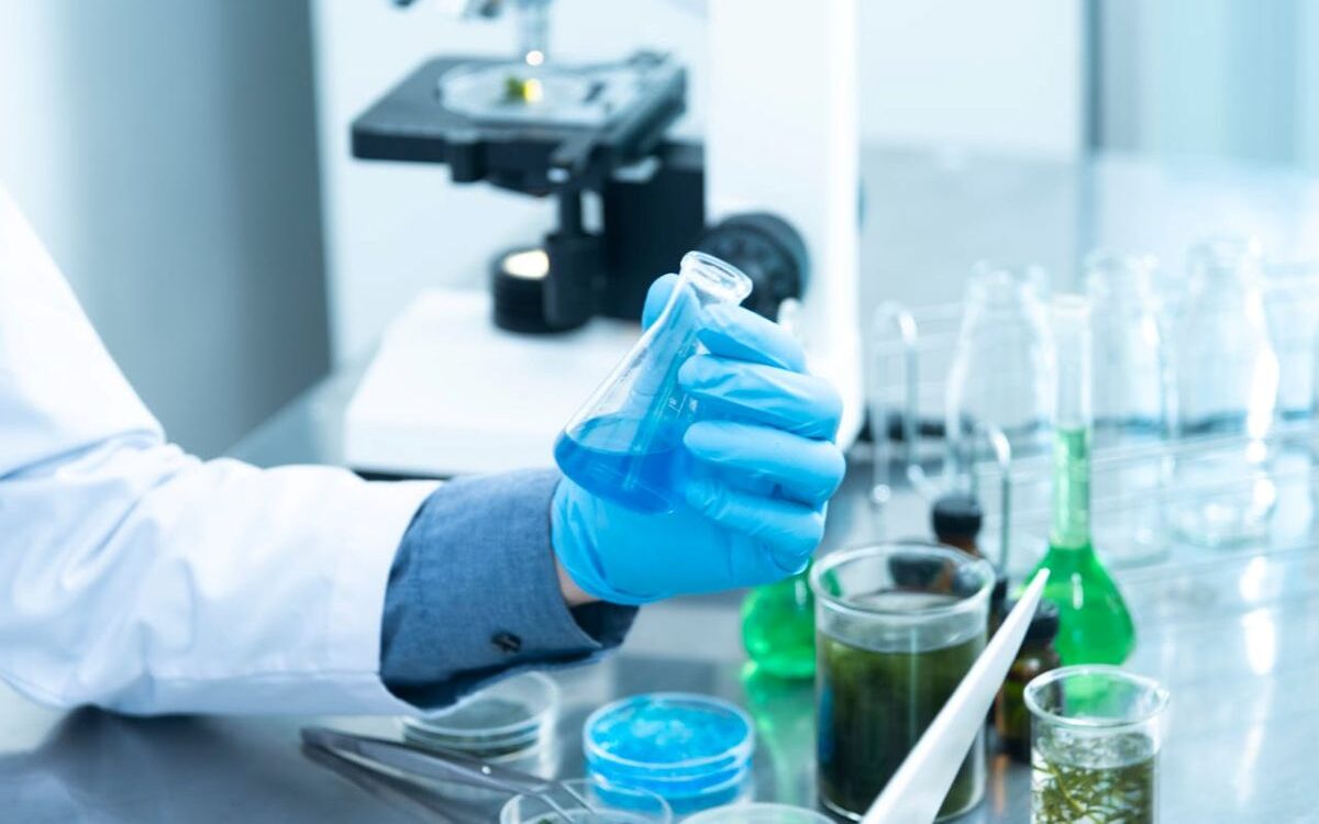 UK-Drug-Pricing-Pressure-Threatens-Pharma-Investment-and-Competitiveness-resized Person wearing gloves in a laboratory holding a test tube