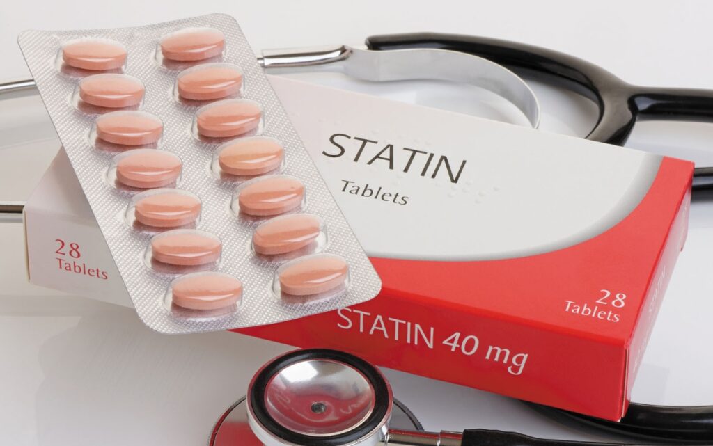 A box of statin medication with tablets and a stethoscope, illustrating a major 2026 scientific review on cholesterol-lowering drug safety.