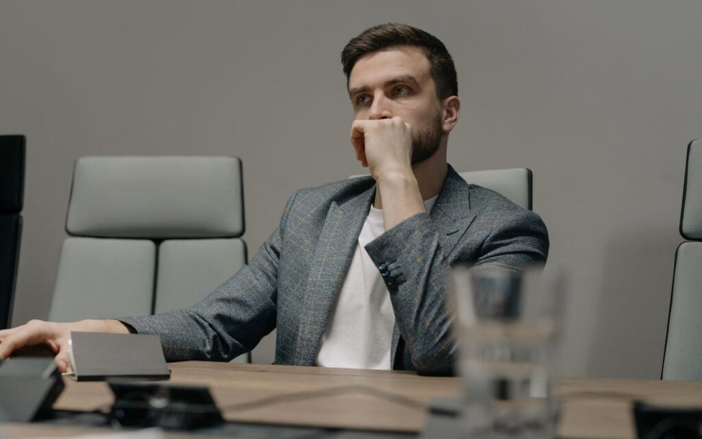 upward bullying in healthcare — senior leader sitting alone at boardroom table looking stressed