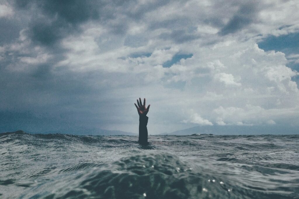 Healthcare worker burnout — hand reaching out of stormy ocean waves