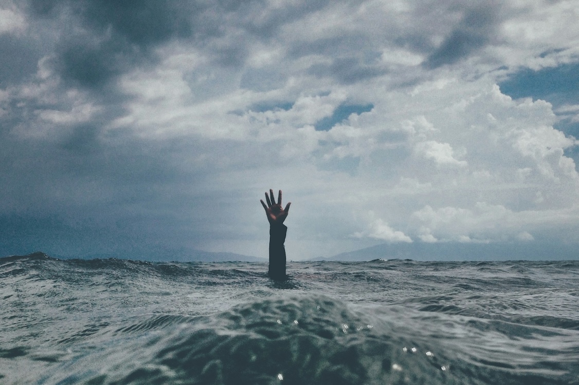Healthcare worker burnout — hand reaching out of stormy ocean waves