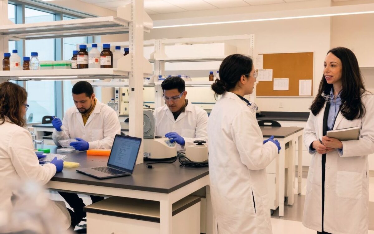 Scientists in white lab coats conducting cell and gene therapy research in a modern biotech laboratory