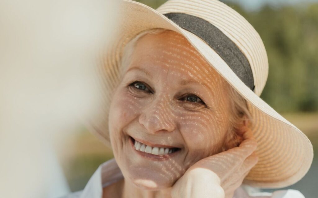 Older woman wearing a wide-brimmed sun hat to protect against actinic keratosis and sun damage