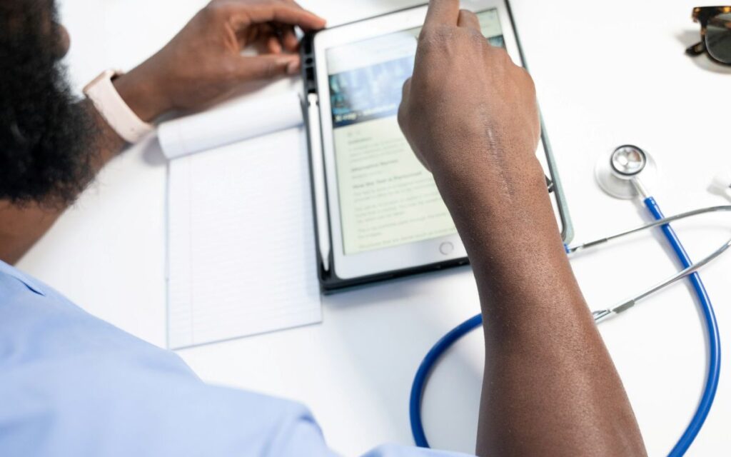 Healthcare professional reviewing care matching data on a tablet beside a stethoscope and notepad