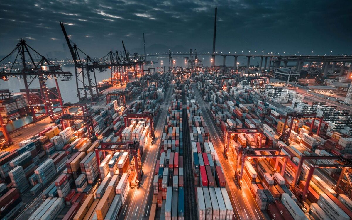 timelab-sWOvgOOFk1g-unsplash-2-scaled Aerial view of a container port at night with cranes and shipping containers tied to lab consumable manufacturing